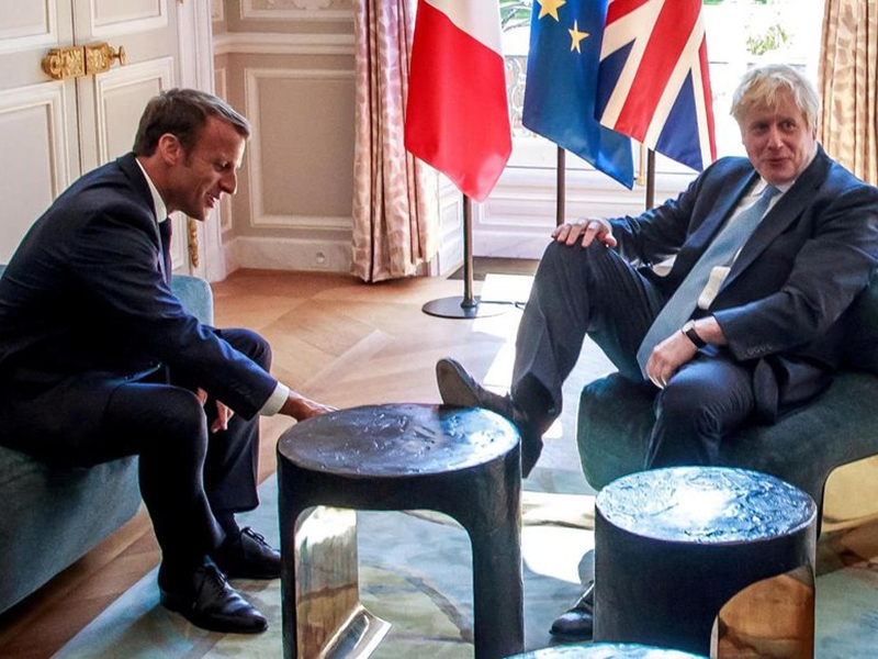 british prime minister boris johnson puts his shoes on the table in front  of french president emmanuel macron